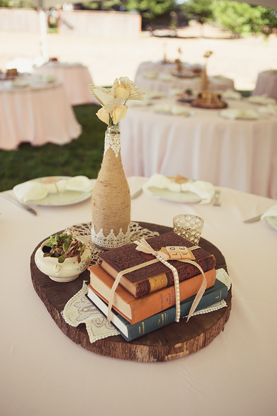 Rustic wedding table centerpiece with books and a flower vase