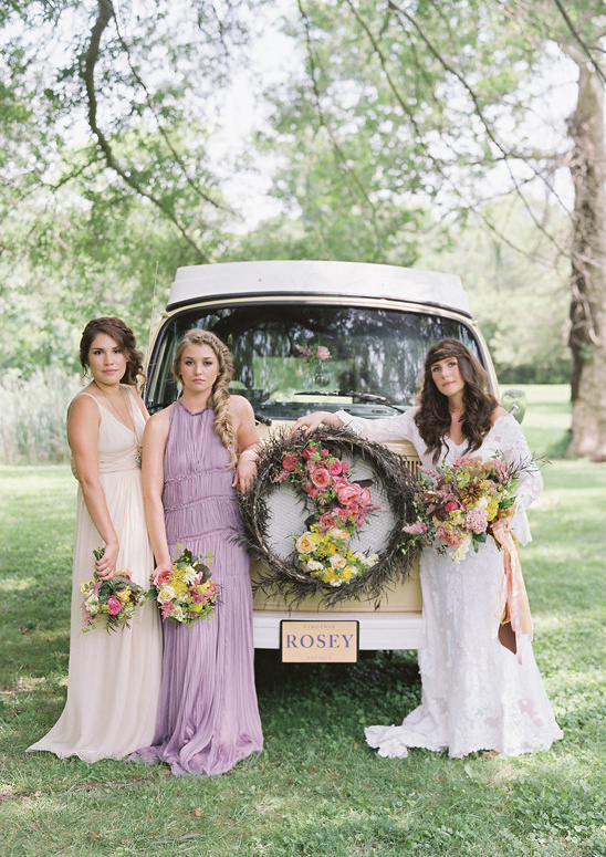 Bridesmaids pose with a vintage car adorned with flowers for a wedding