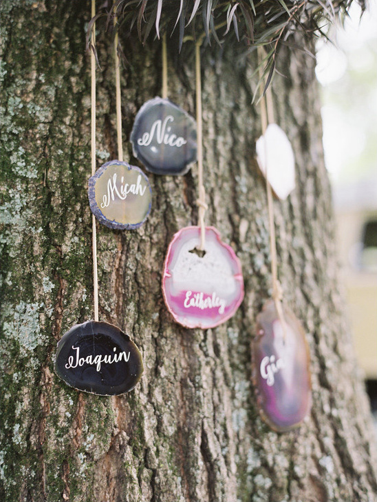 Wedding name tags hang on tree bark for guests