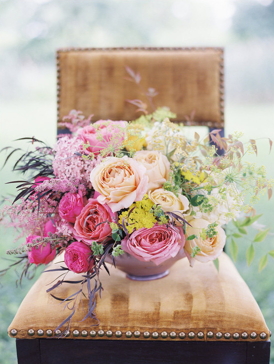 Colorful floral bouquet on a gold velvet chair and a dark wood frame