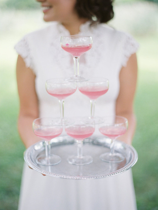 Woman holding a tray with a pyramid of pink champagne glasses