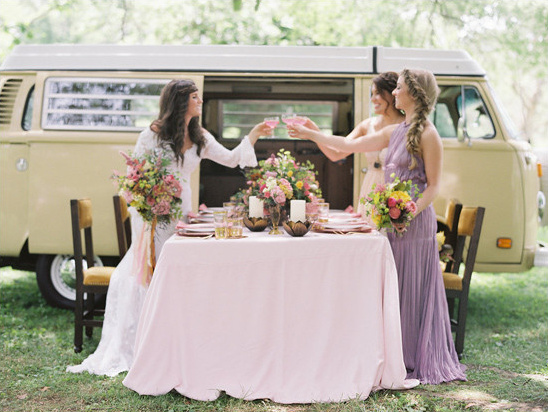 Wedding toast with friends next to vintage camper van, flowers