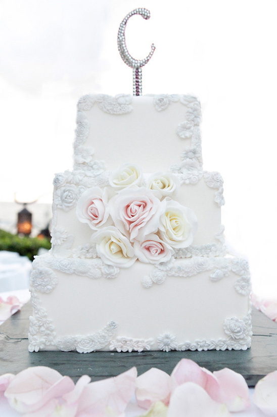 Elegant white wedding cake with floral decorations and a C topper