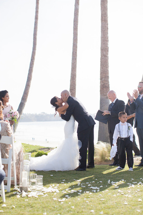 Bride and groom share first kiss at beachfront wedding