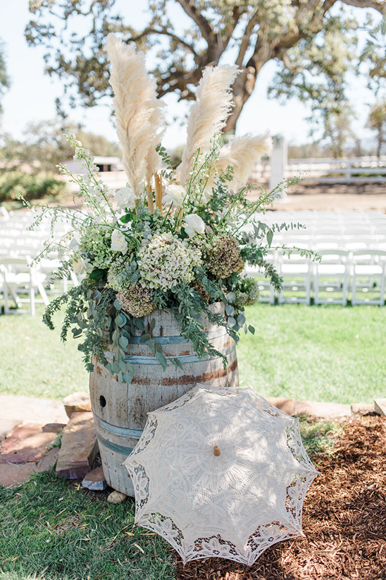 Wedding decor with flowers in barrel and lace parasol