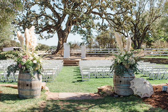 Outdoor wedding ceremony setup with barrels and floral arrangements