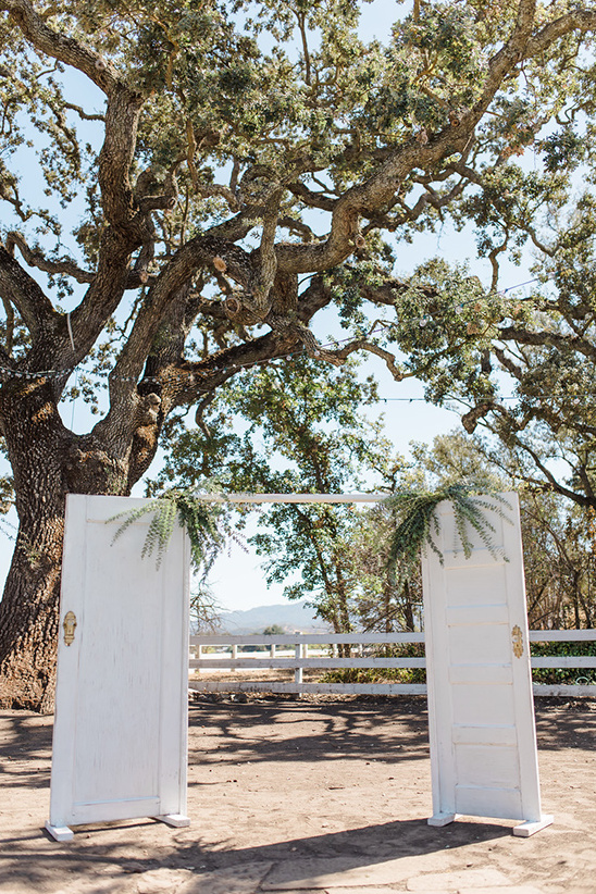 Rustic wedding archway made of doors under a large tree