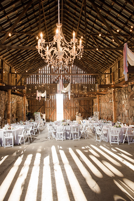 Elegant barn wedding reception with crystal chandelier and tables