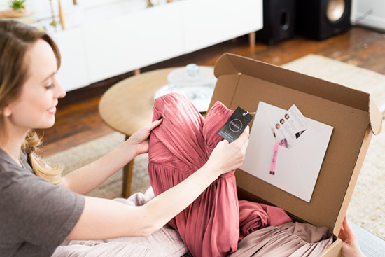 Woman unboxing a new pink dress from online order