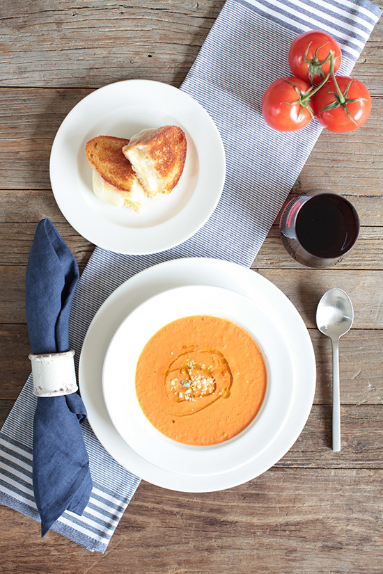 Tomato soup grilled cheese and wine lunch on rustic table