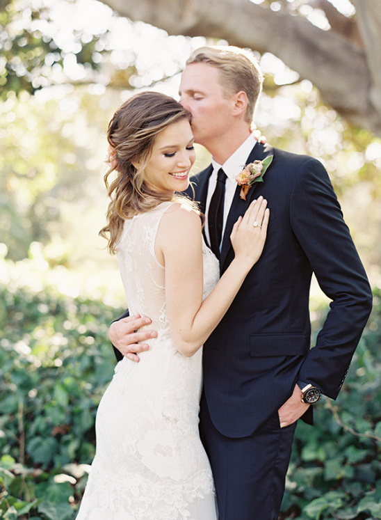 Groom kisses bride on forehead in loving wedding portrait