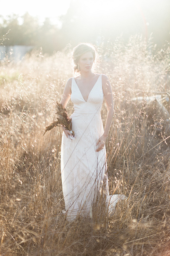 Bohemian bride in white dress in sunny grass field