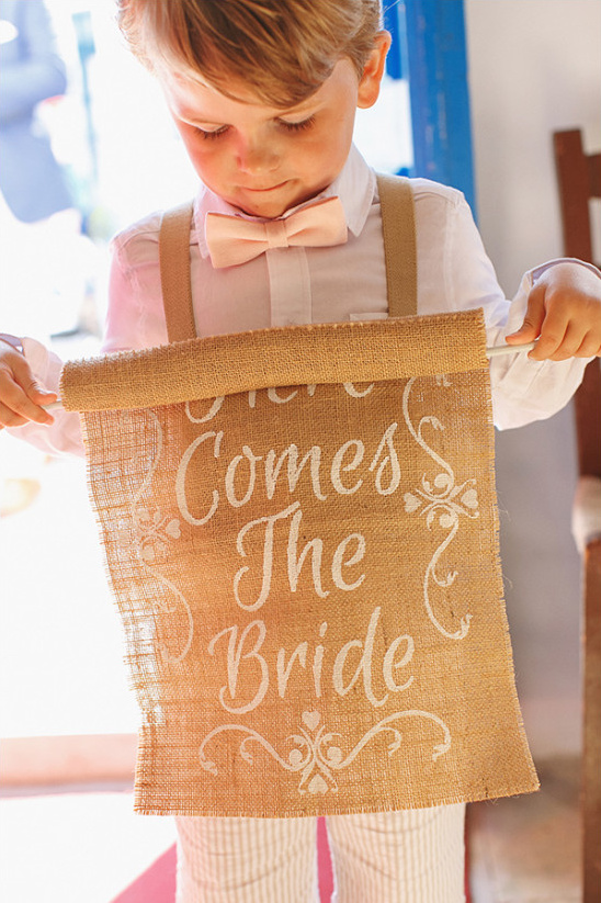 Ring bearer with Here Comes The Bride sign at wedding