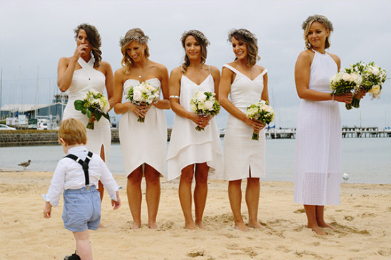 Bridesmaids in white dresses on beach with cute ring bearer