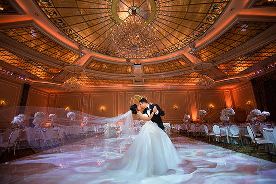 Bride and groom kiss on elegant ballroom dance floor