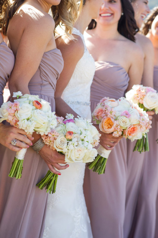 Bridesmaids holding peach and white floral bouquets
