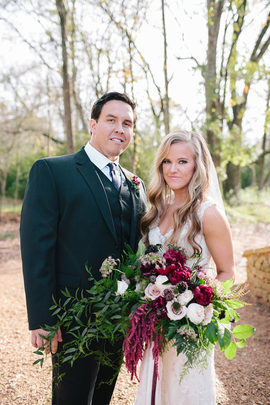 Bride and groom pose with bouquet outdoors wedding