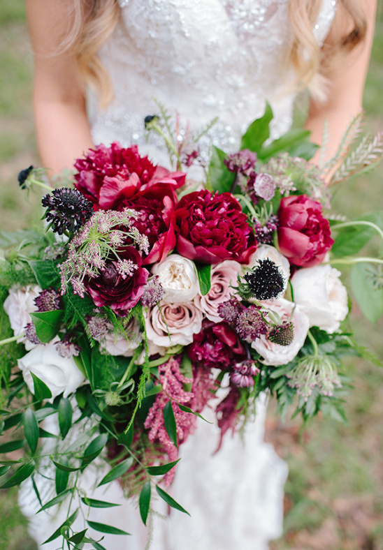 Bride in lace dress holds a colorful wedding bouquet