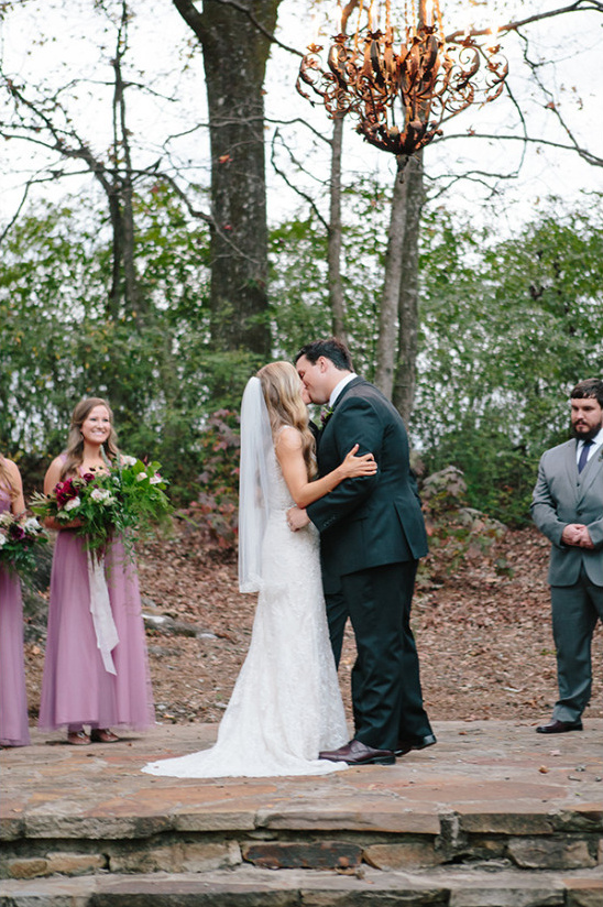 Bride and groom kiss at outdoor wedding ceremony