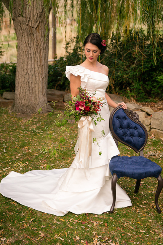Bride in elegant white gown poses with floral bouquet