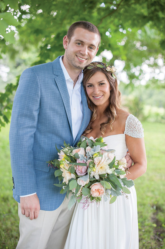 Bride and Groom embrace holding floral bouquet