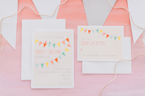 Colorful banner flags on pink wedding invitation cards