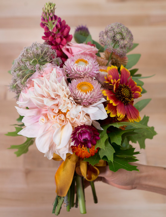 Hand holding colorful spring flower bouquet with ribbon