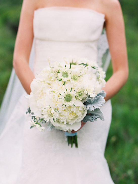 Elegant bride holds white peony and dusty miller bouquet