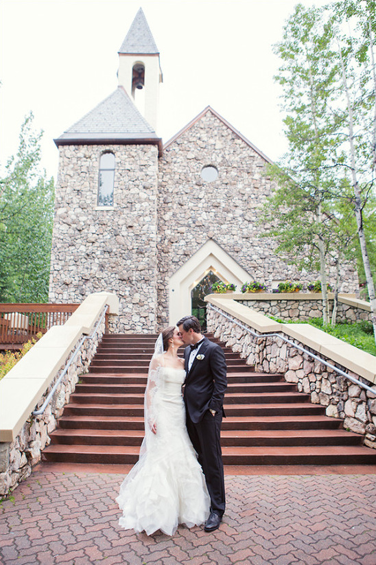 Bride and groom kiss at stone church wedding venue