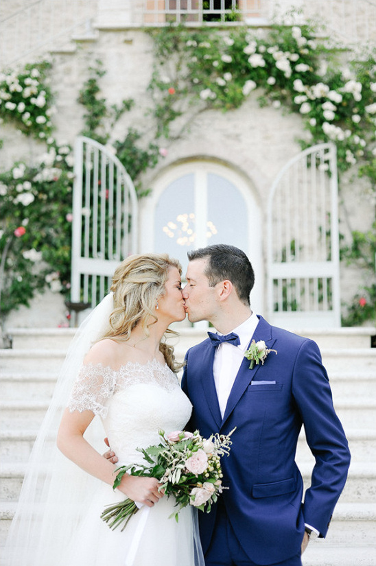 Romantic wedding kiss of bride and groom with white flowers