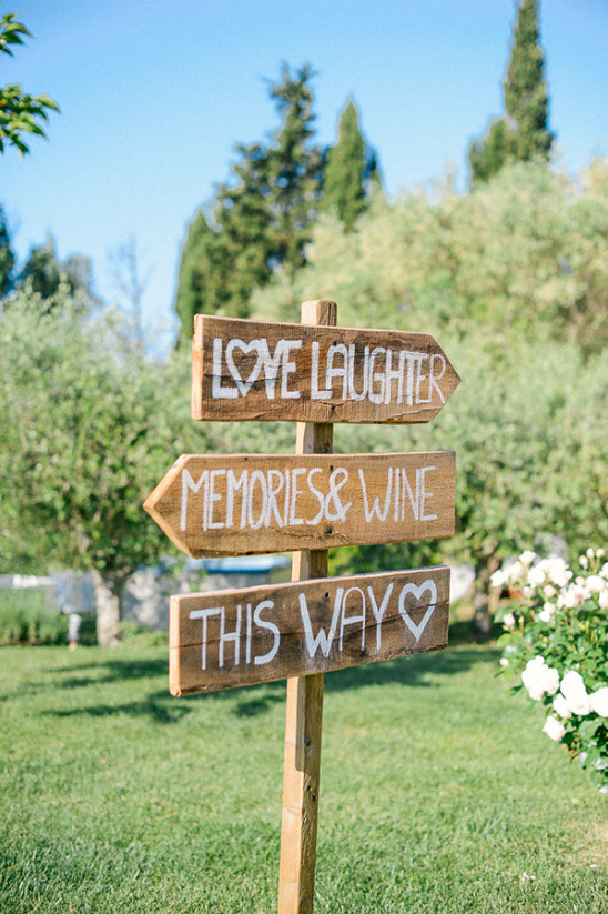 Rustic wooden signpost points to love laughter memories wine