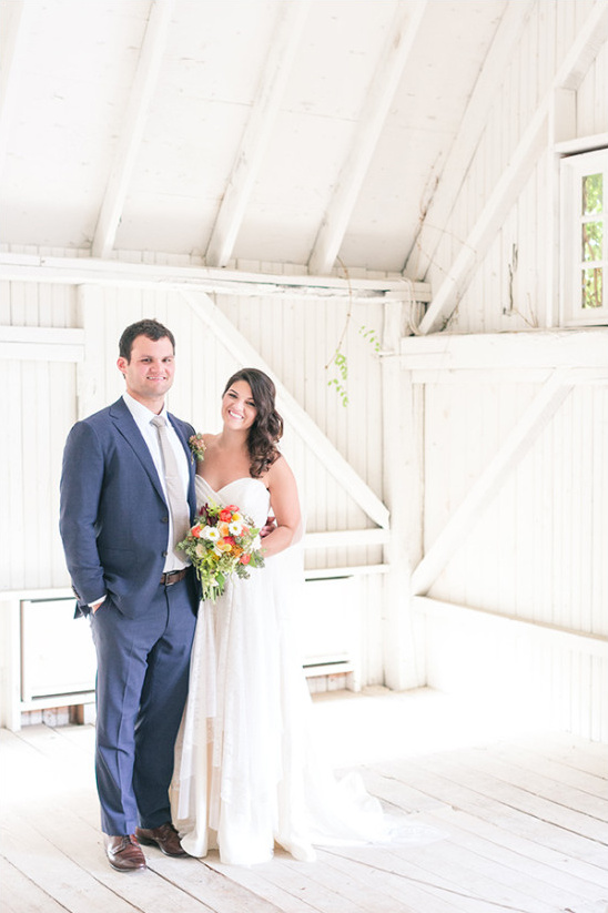 Bride and groom pose in a white barn wedding venue