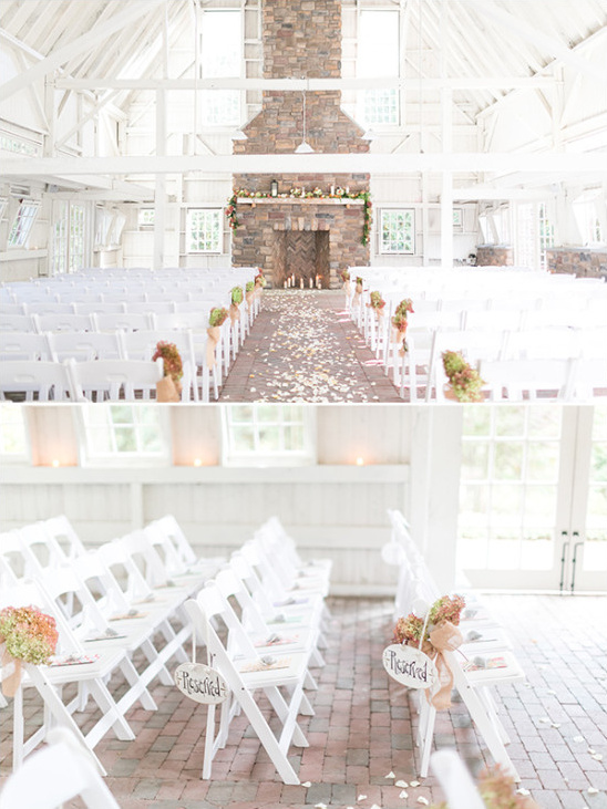 White wedding venue with rows of chairs and stone fireplace