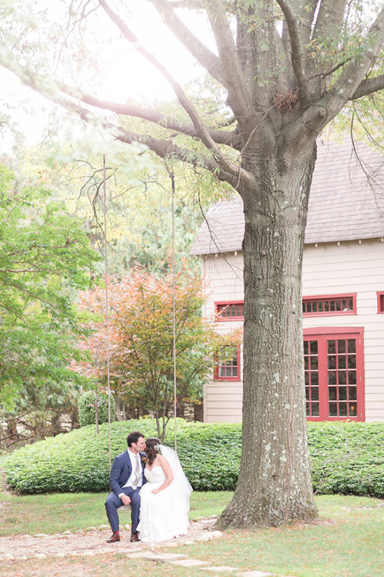 Bride and groom kiss on a tree swing wedding day