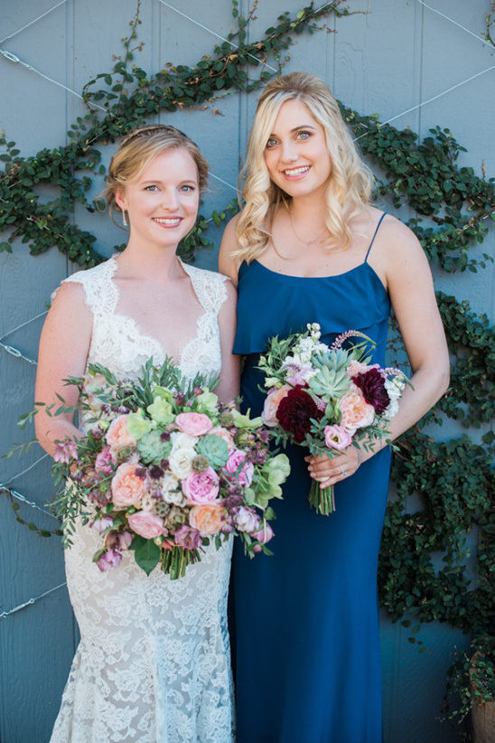 Bride and bridesmaid in wedding attire, holding bouquets
