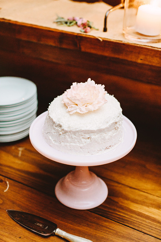 Pink-frosted cake with flower, on pink stand