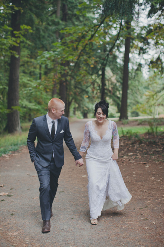 Newlyweds stroll hand in hand through a forest path