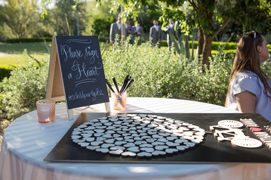 Sign a heart guest book at outdoor wedding reception