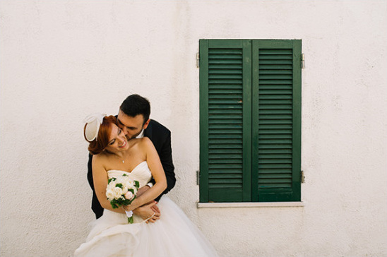 Bride and groom embrace near green shutters wedding day