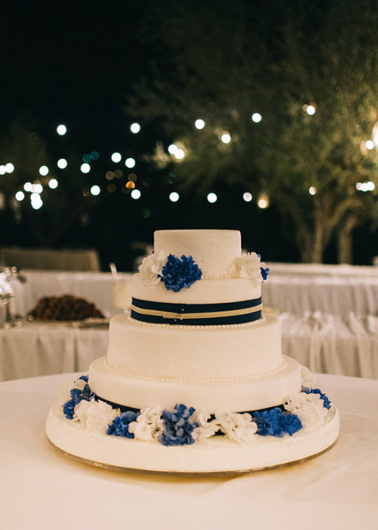 Elegant four-tier wedding cake with blue flowers