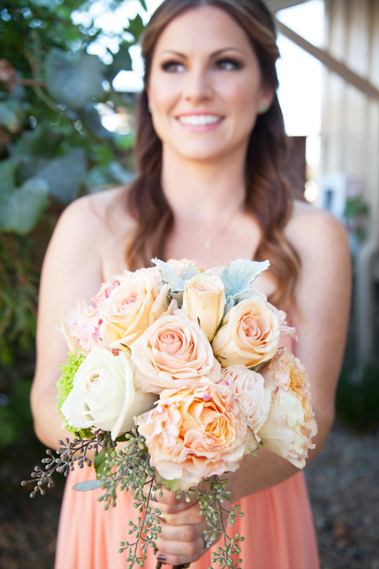 Bridesmaid holds a peach and cream rose bouquet