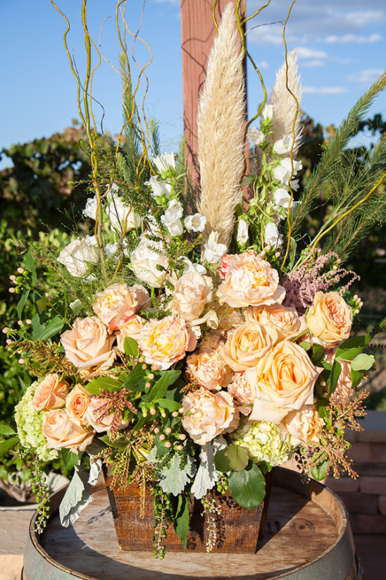 Peach rose arrangement in wooden box on wine barrel