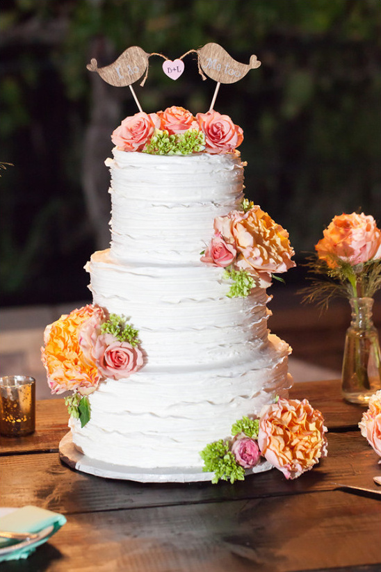 Three tier wedding cake with flowers and bird topper
