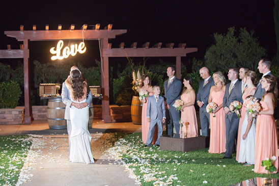 Bride and groom embracing under Love sign at wedding party