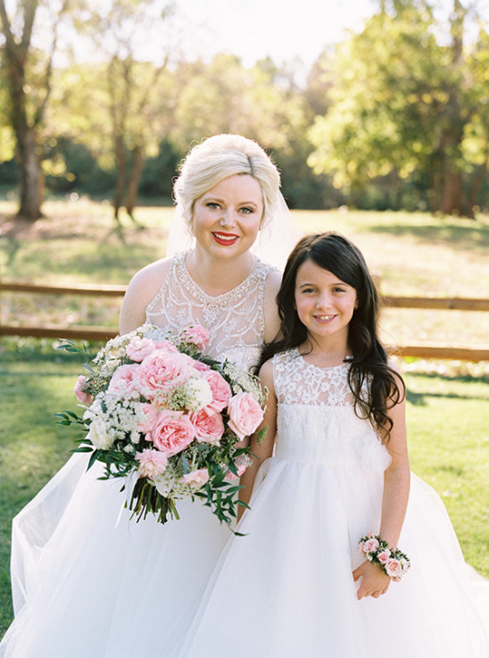 Bride and flower girl smiling with pink wedding bouquet