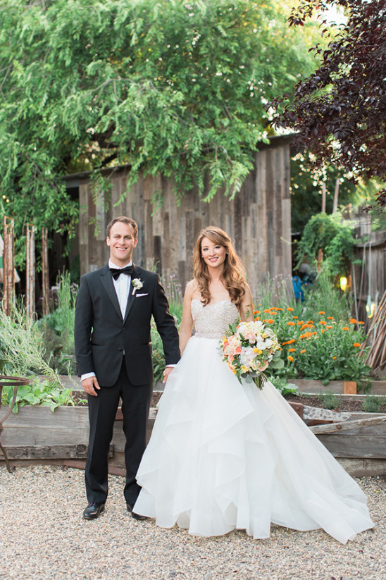 Happy wedding couple holds hands in garden setting