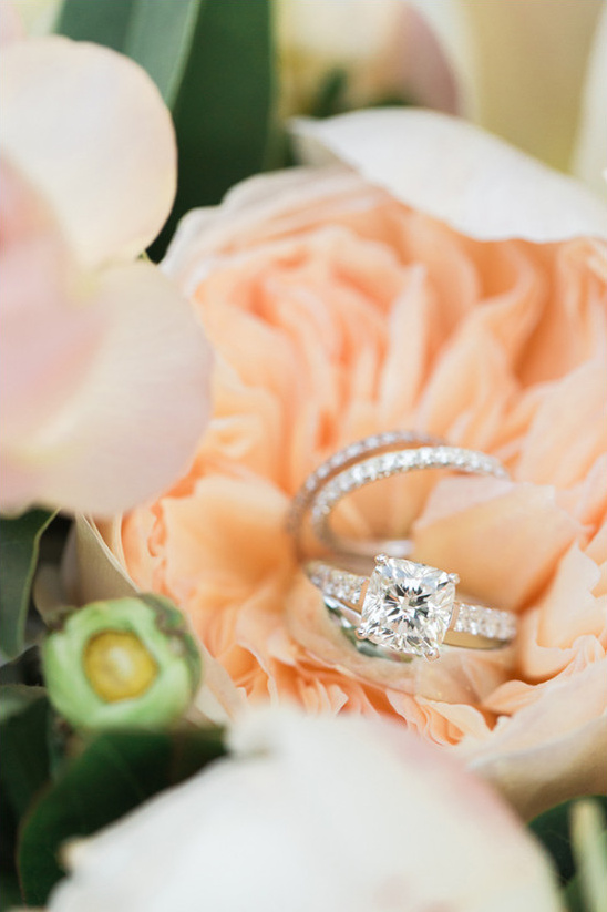 Diamond wedding rings nestled in delicate peach flowers