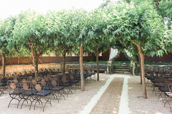 Outdoor wedding ceremony aisle with rustic chairs under trees