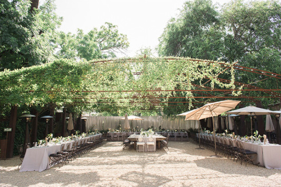 Outdoor wedding reception under a vine-covered arbor