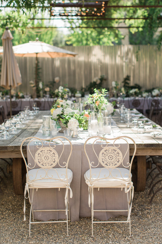 Outdoor wedding reception table setting with white chairs